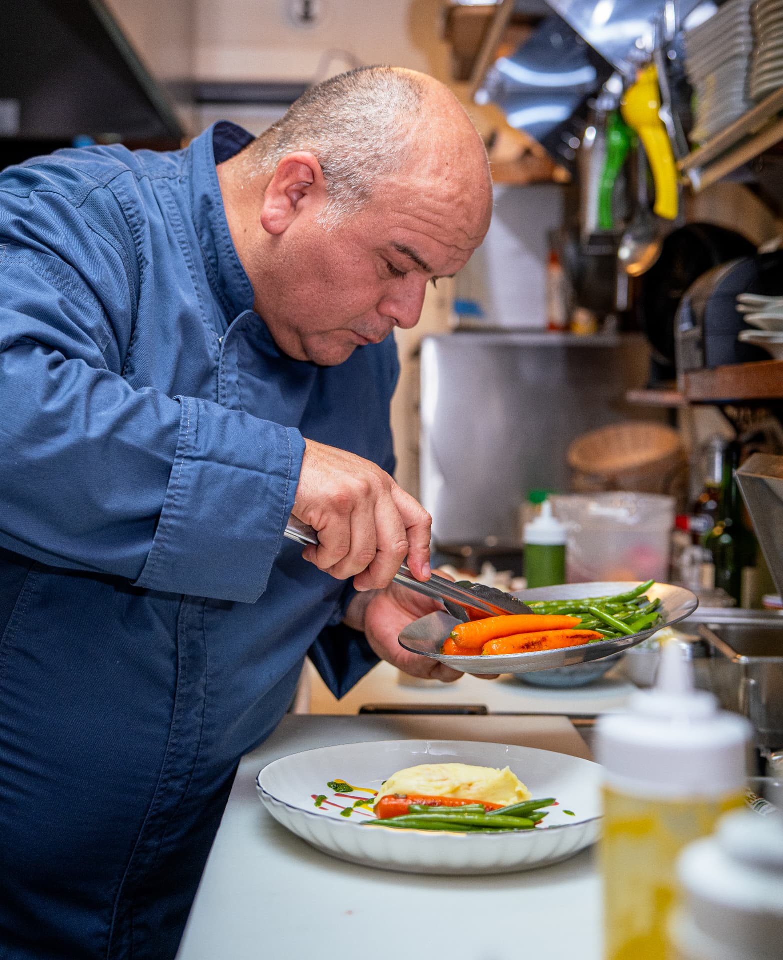 The head chef plating grilled carrots and green beans in the Marazul kitchen